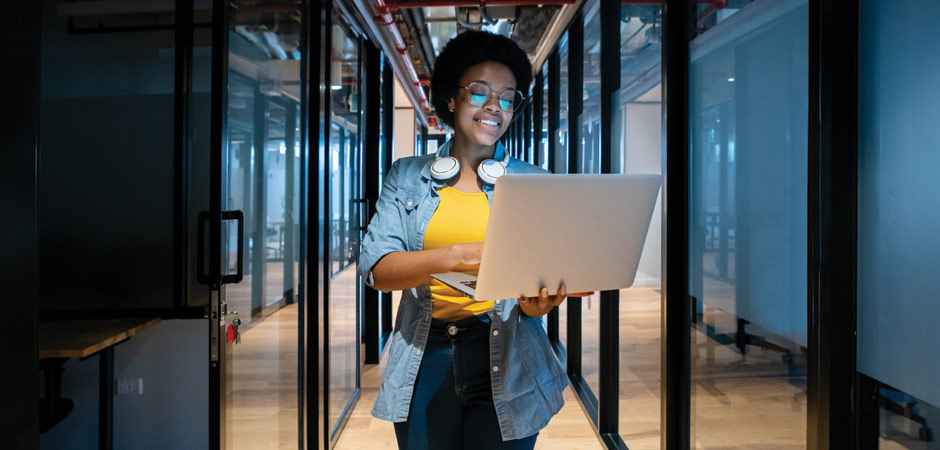 Woman walking while using laptop